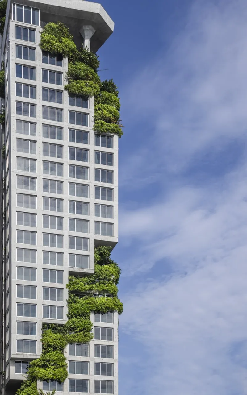 Detail of the planted terraces cascading down the tower under a blue sky with light clouds