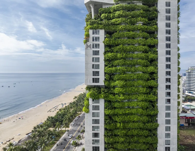 Tower facade with planted terraces facing the beachfront road lined with palm trees