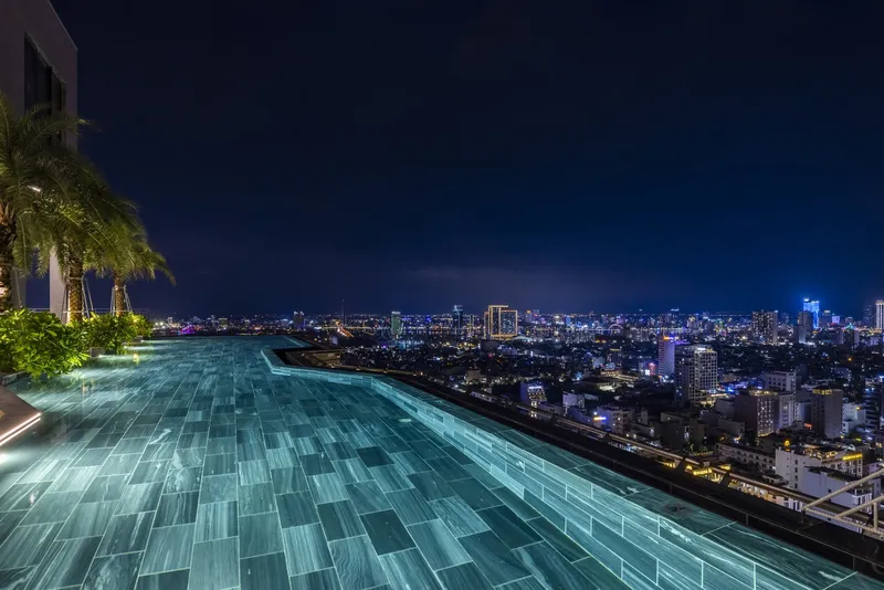 Infinity edge pool on the rooftop terrace overlooking the illuminated cityscape at night