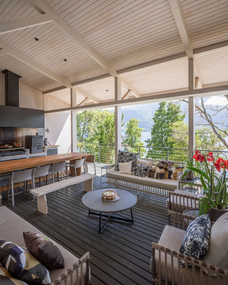 Covered deck with timber slat ceiling and cable railing overlooking treetops and distant mountains