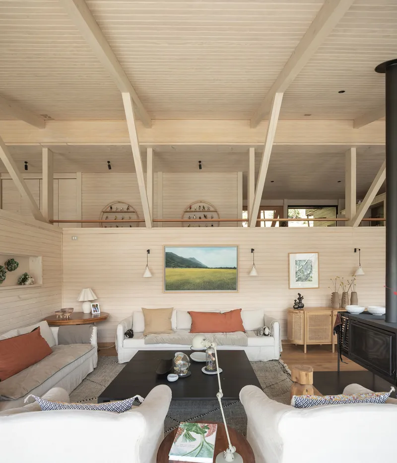Double-height living room with exposed timber beams and an open mezzanine above the seating area