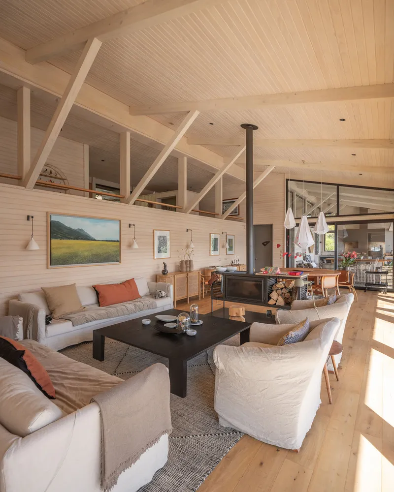 Open-plan living space with wood-burning stove and exposed timber ceiling trusses in daylight