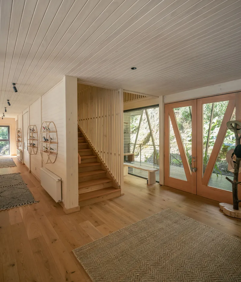 Entry hall with vertical slat screen enclosing the timber staircase and glazed doors beyond
