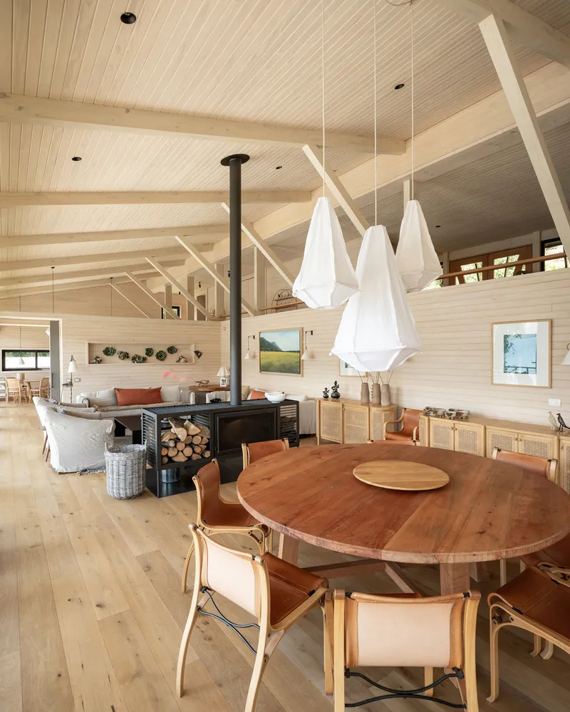 Circular dining table beneath white pendant lights with wood-burning stove in the background