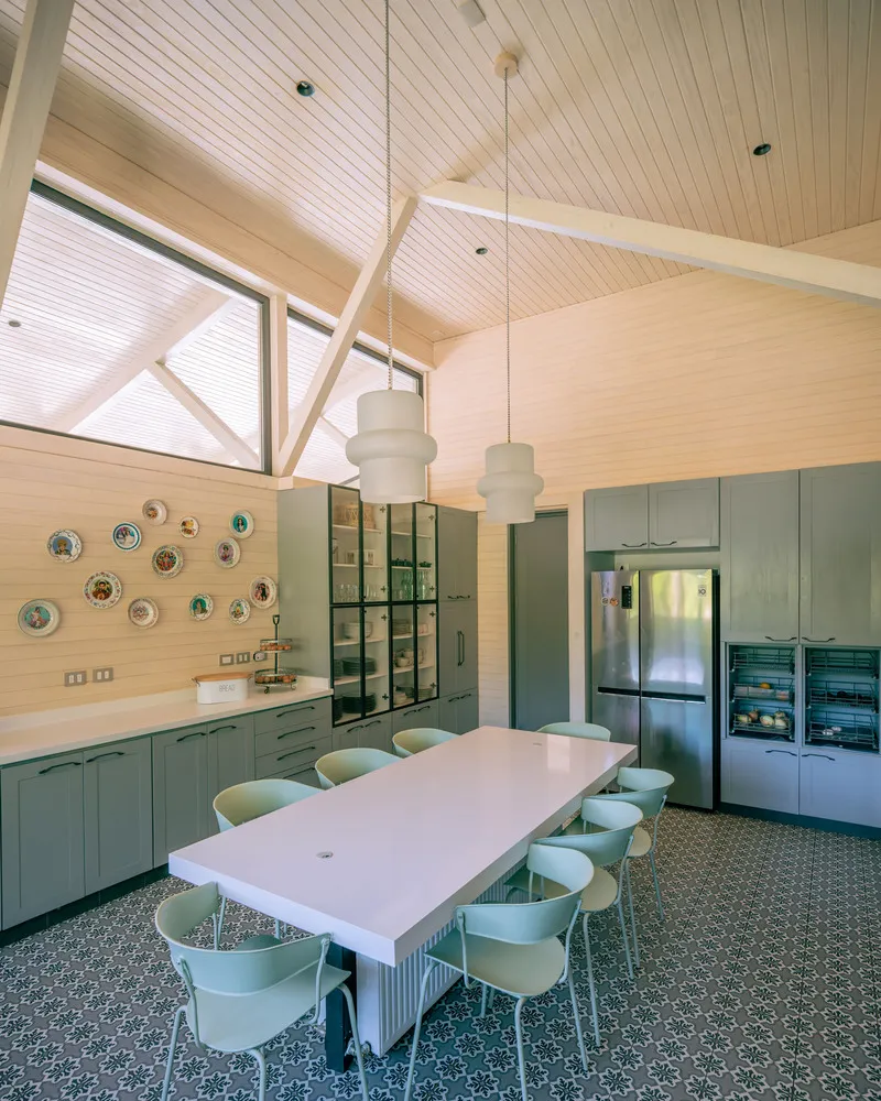 Kitchen with sage-green cabinetry, terrazzo flooring and clerestory windows admitting afternoon light