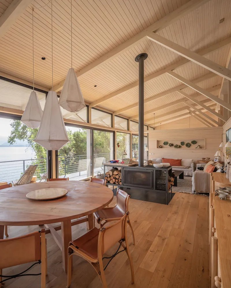 Living area with vaulted wood ceiling and floor-to-ceiling windows overlooking the waterfront
