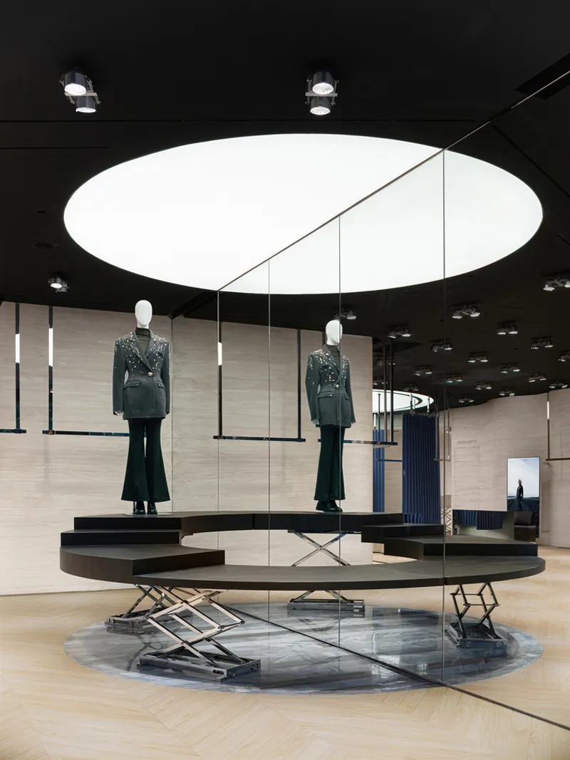 Tiered display platforms with mannequins under a circular ceiling oculus in a retail interior