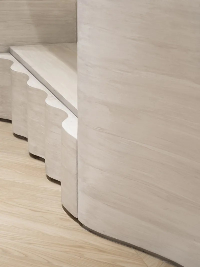 Detail of curved pale wood veneer wall panel with routed horizontal slots