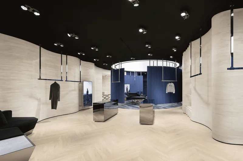View across herringbone wood flooring toward cylindrical blue curtain enclosure with circular skylight above