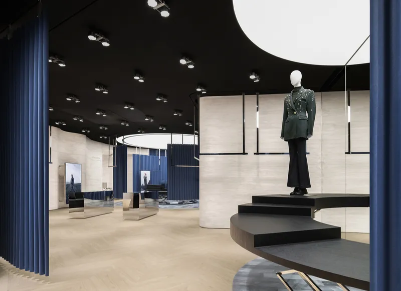 Retail interior with cantilevered black steps, curved blue fabric partitions and pale wood walls beneath a black ceiling