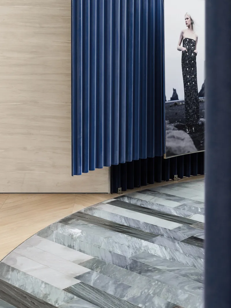 Blue vertical panel radiator beside a doorway with striped marble flooring and fashion photograph beyond