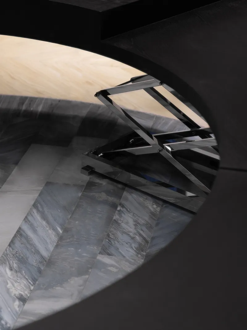 Angled glass balustrade reflecting striped marble floor beneath a curved black ceiling plane