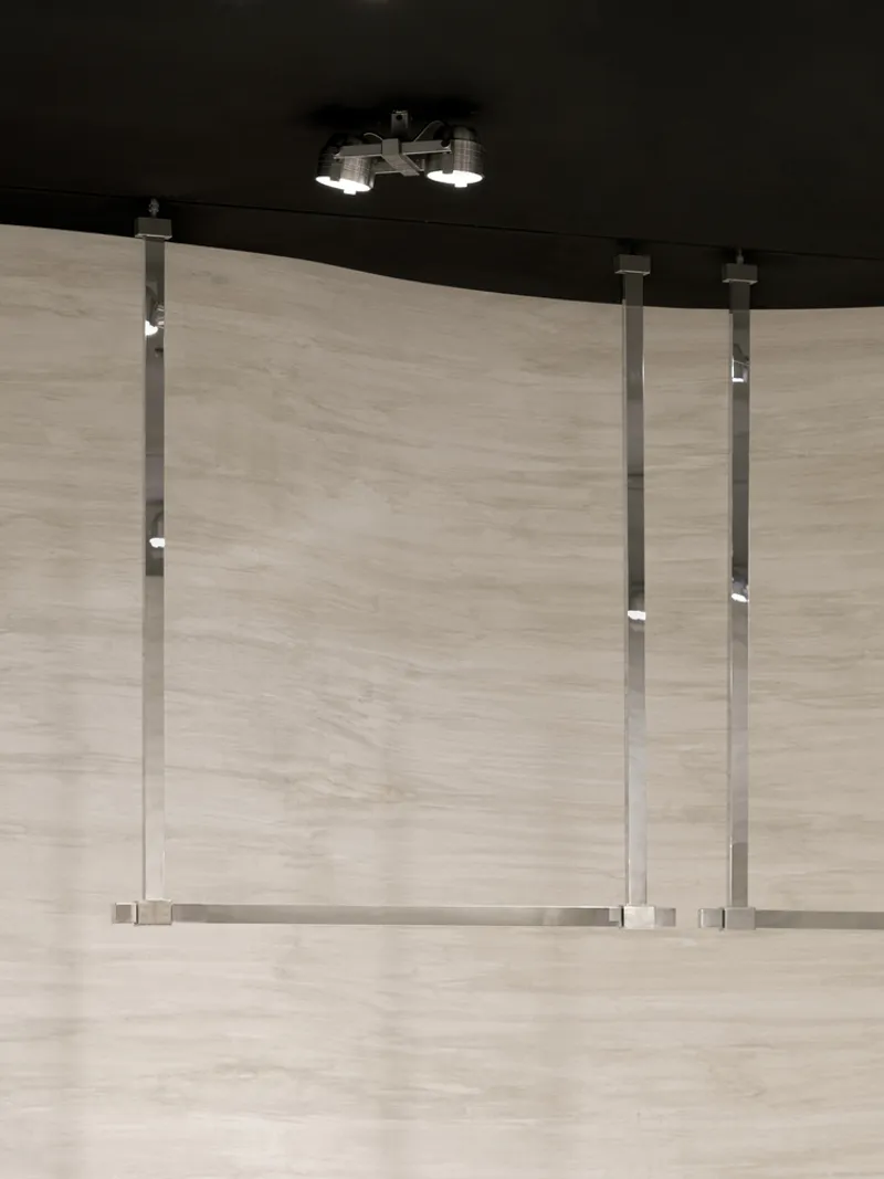 Glass balustrade with metal posts and horizontal rails under a black ceiling with suspended lighting