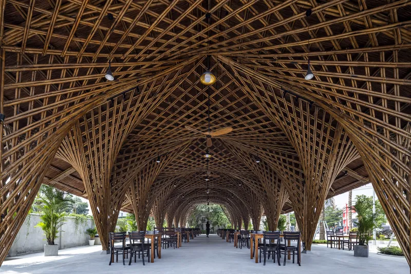 Interior view along bamboo lattice columns supporting the vaulted ceiling with dining tables below