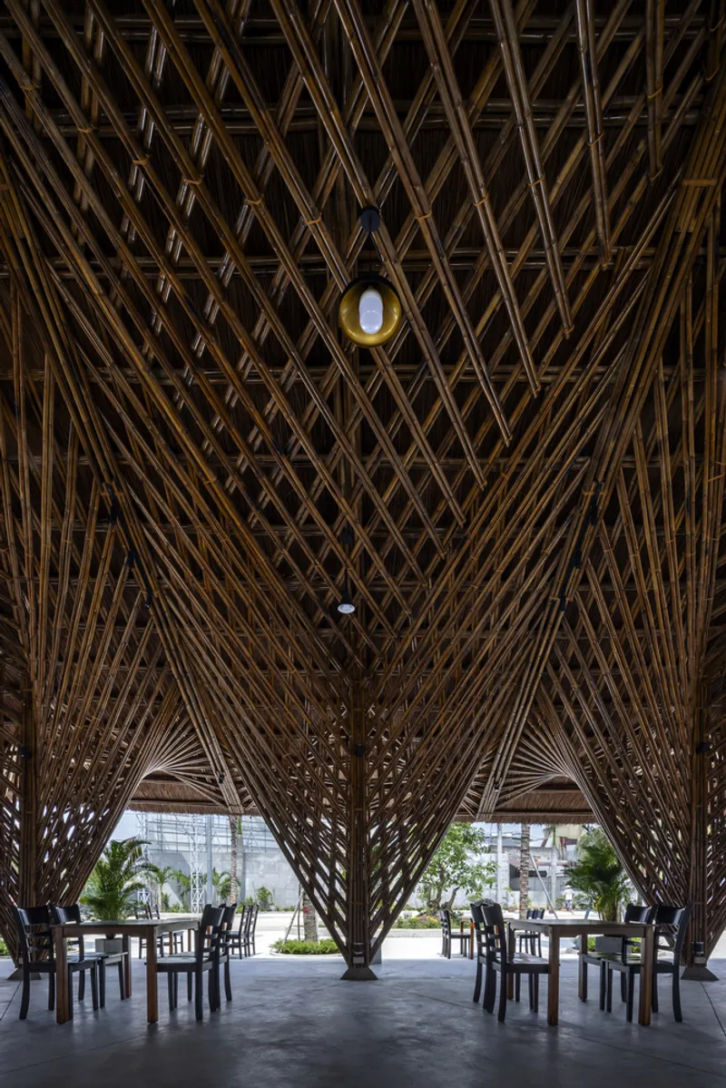 Looking up at converging bamboo trusses with a single pendant light at the peak