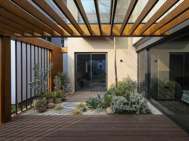 Terrace courtyard with timber decking, gravel beds, succulents and timber beam pergola overhead