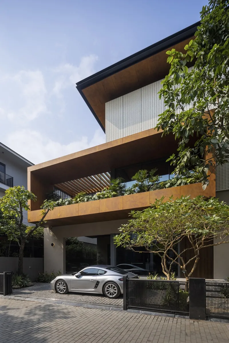 Street view of the layered timber-clad facade with perforated metal panels and mature trees