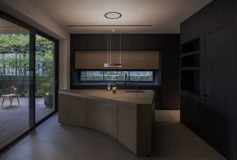 Kitchen with central island, black cabinetry and horizontal slot window overlooking bamboo courtyard