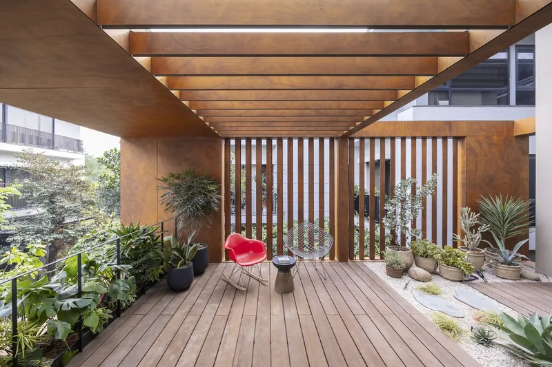 Upper-level terrace with timber decking, vertical wood slat screens and potted plants under exposed beams