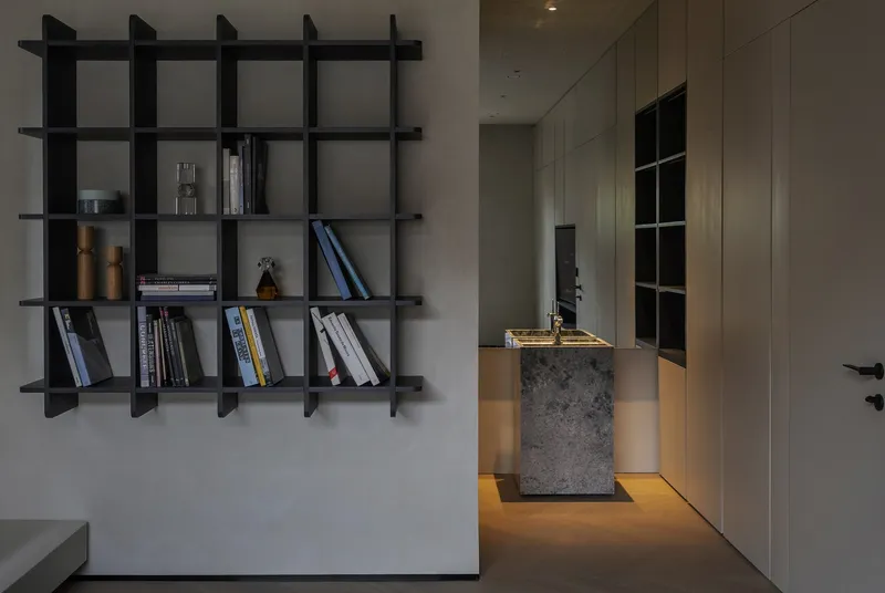 Black grid shelving unit and illuminated concrete bar with recessed floor lighting at dusk