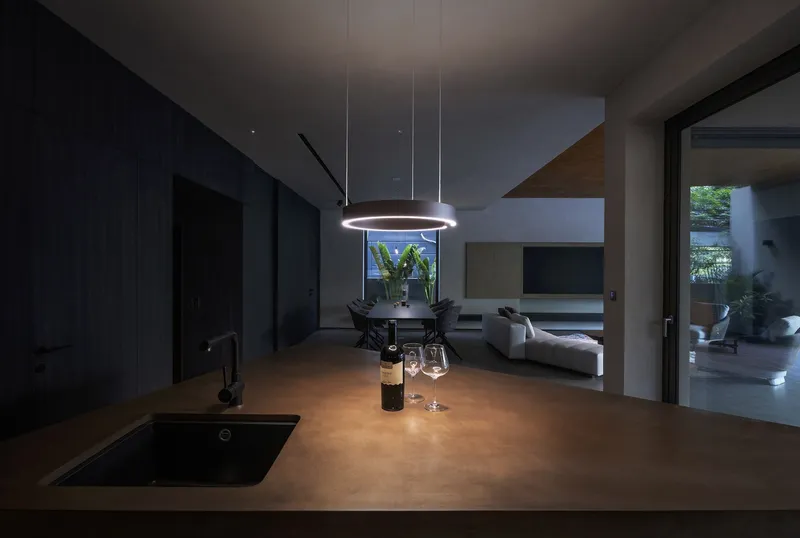 Kitchen island with circular pendant light overlooking dining and living zones at night