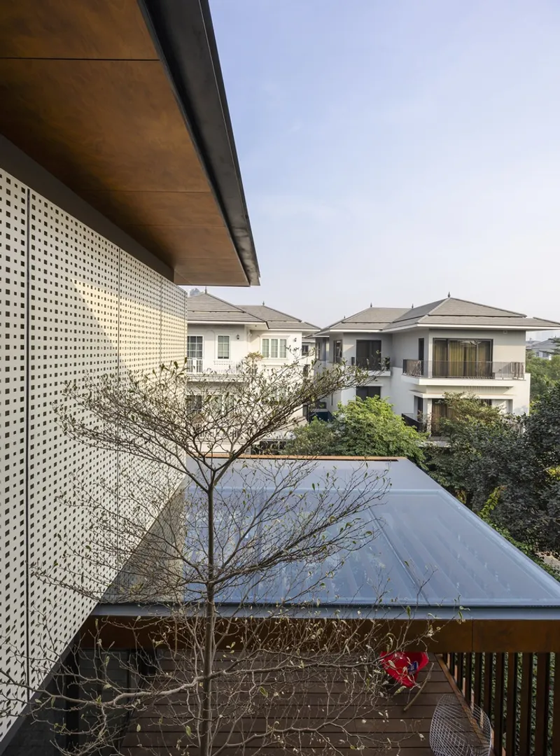 Upper terrace with perforated metal screen and timber soffit overlooking neighboring rooftops and a small tree
