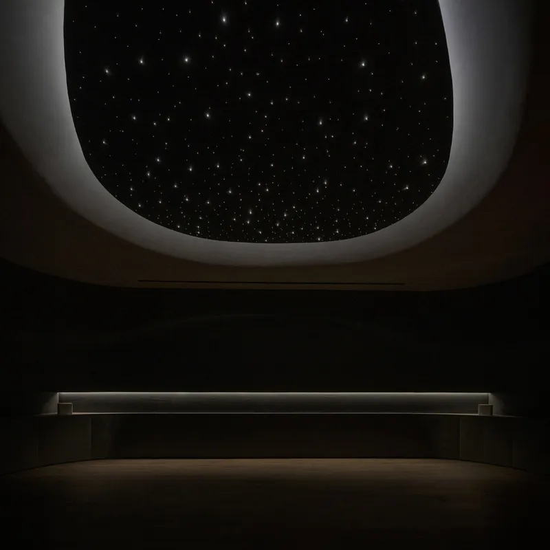 Oval ceiling aperture with embedded fiber optic stars above a backlit stone bench in darkness