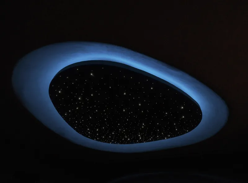 Oval ceiling oculus with fiber optic lighting creating a starfield effect in blue ambient light