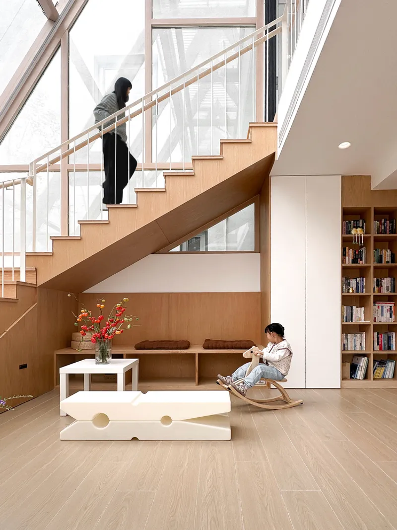 Timber staircase with integrated seating below while a figure ascends toward floor-to-ceiling windows