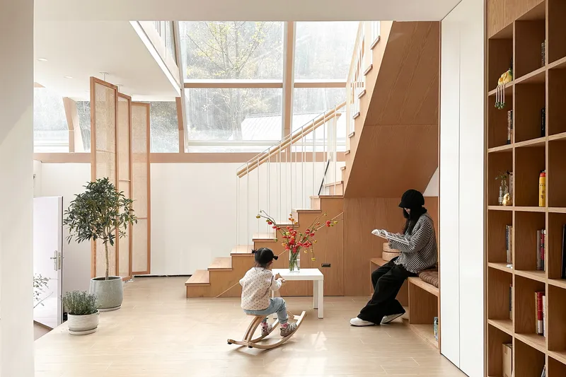 Double-height space with timber stair and skylights as a child plays on a rocking horse