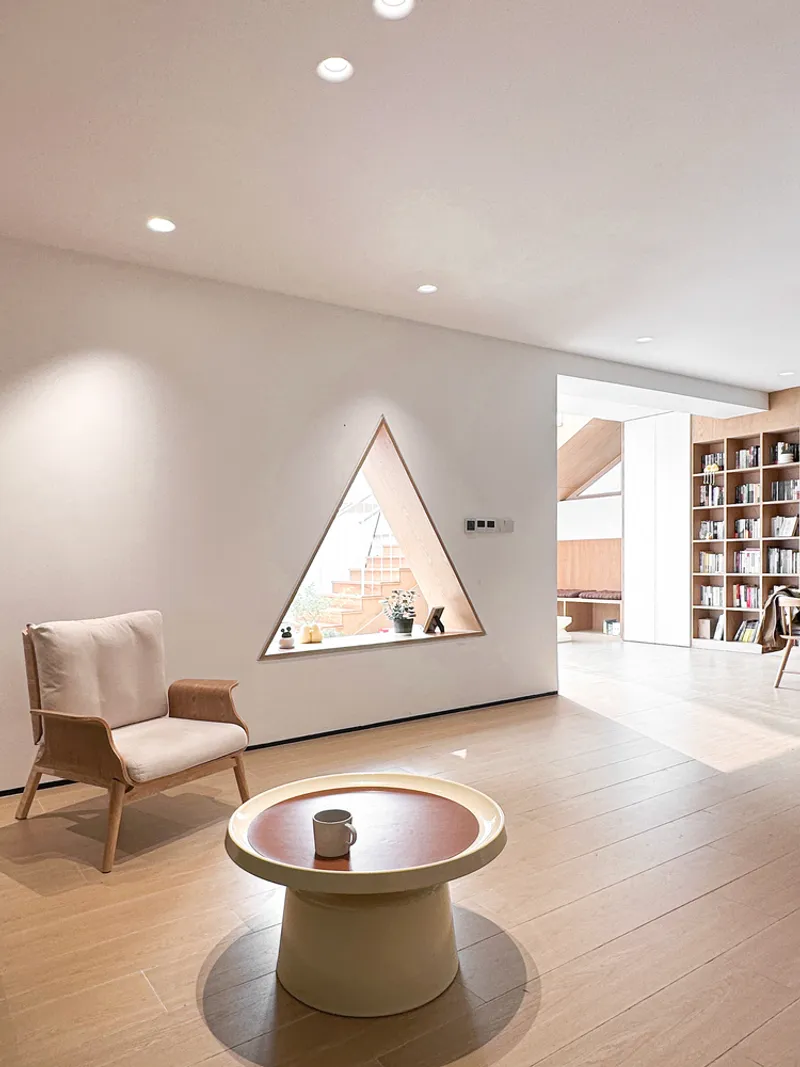 Triangular recessed niche in a white wall with a low pedestal table on pale flooring