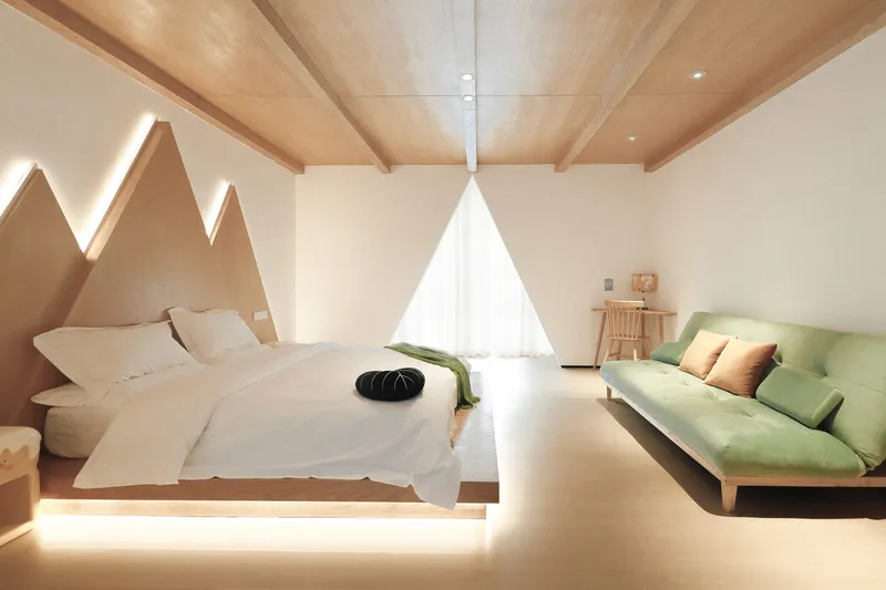 Bedroom suite with floating platform bed under a vaulted timber ceiling and backlit mountain-shaped headboard wall