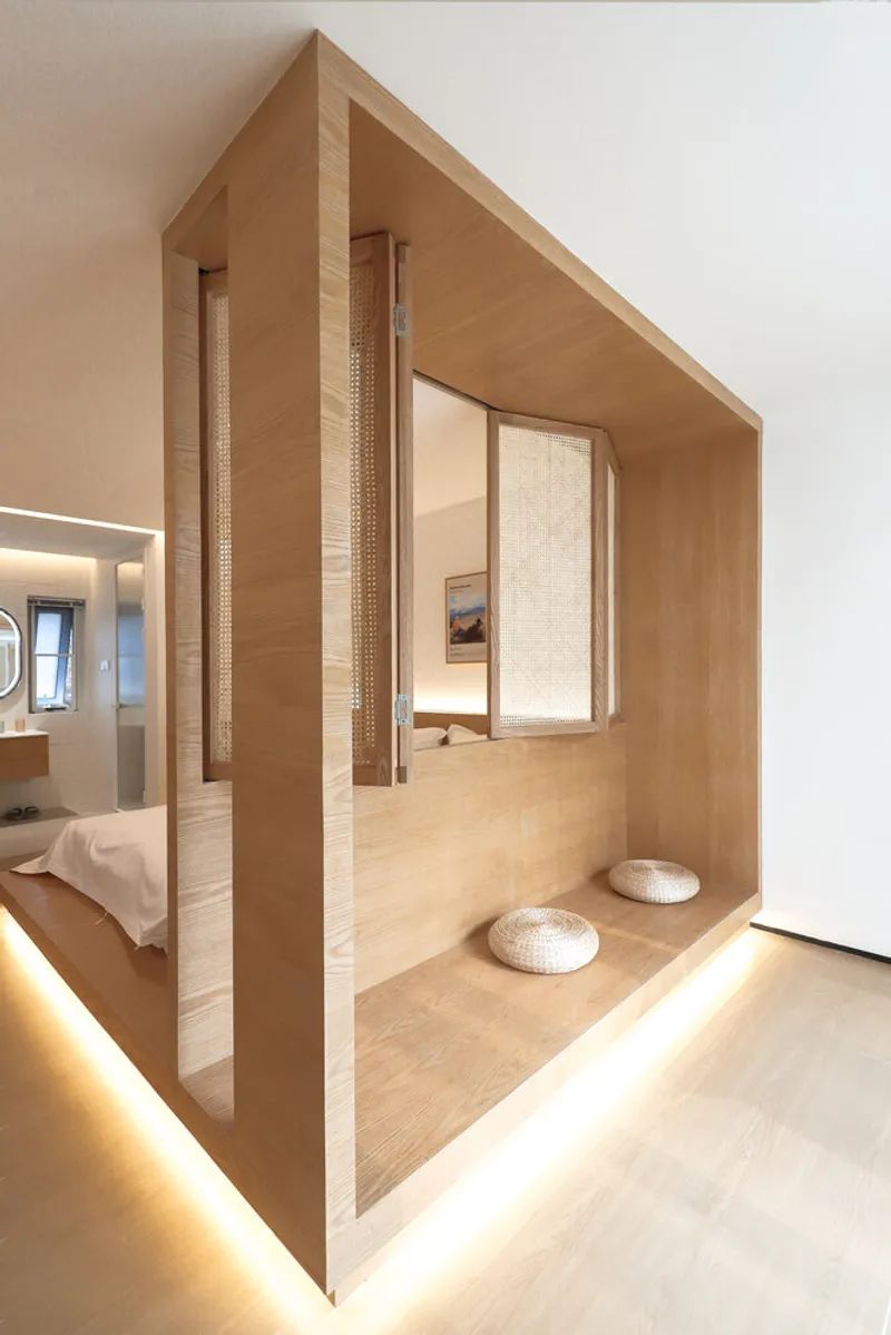 Timber sleeping pavilion with house-shaped profile and sliding woven screens framing an elevated platform with floor cushions