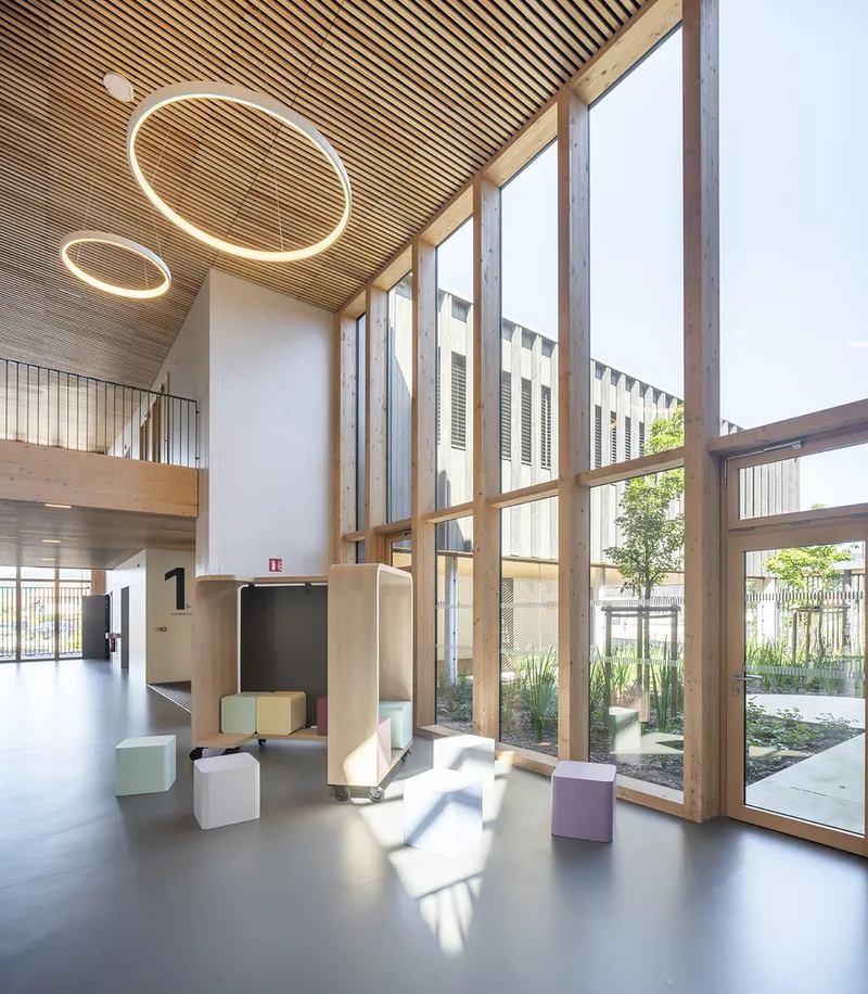 Double-height lobby with circular pendant lights and floor-to-ceiling glazing overlooking planted courtyard