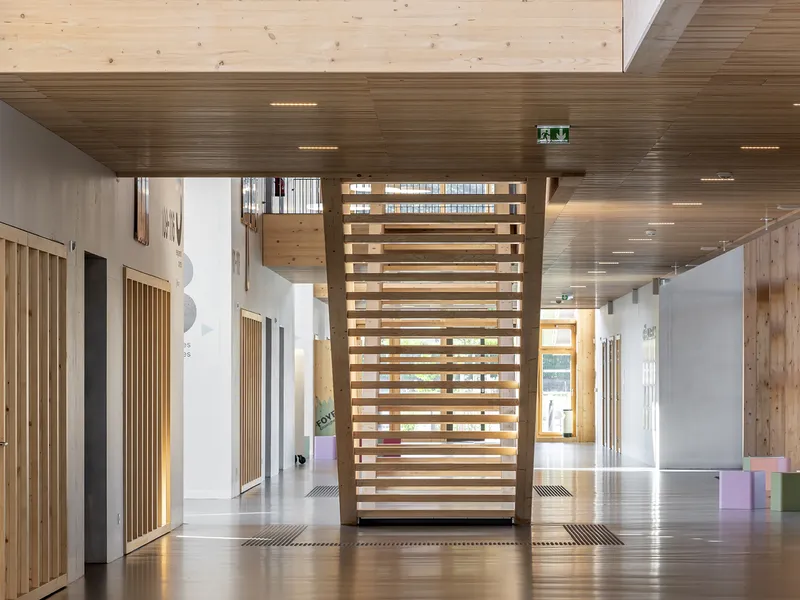 Freestanding timber screen dividing a corridor with slatted ceiling and pale flooring