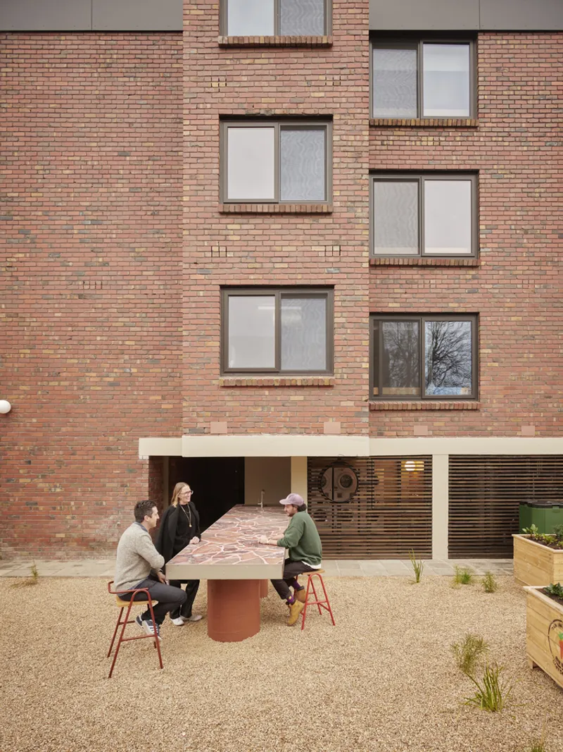 Courtyard table with four people gathered beneath a multicolored brick facade
