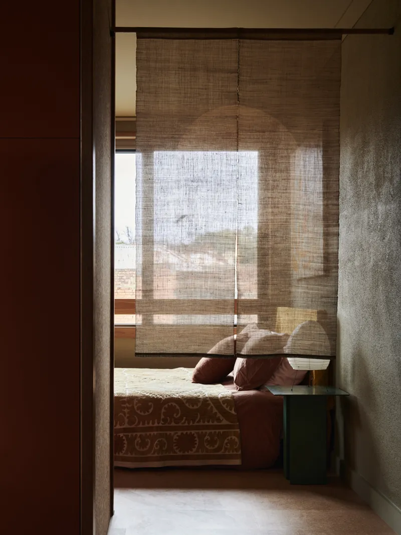 Bedroom doorway with woven shade filtering afternoon light across the floor