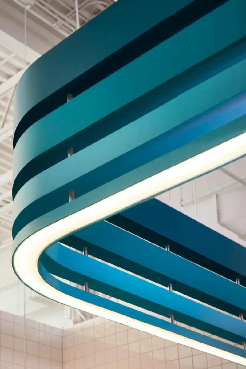 Close-up of layered turquoise balcony edges curving against an exposed ceiling structure