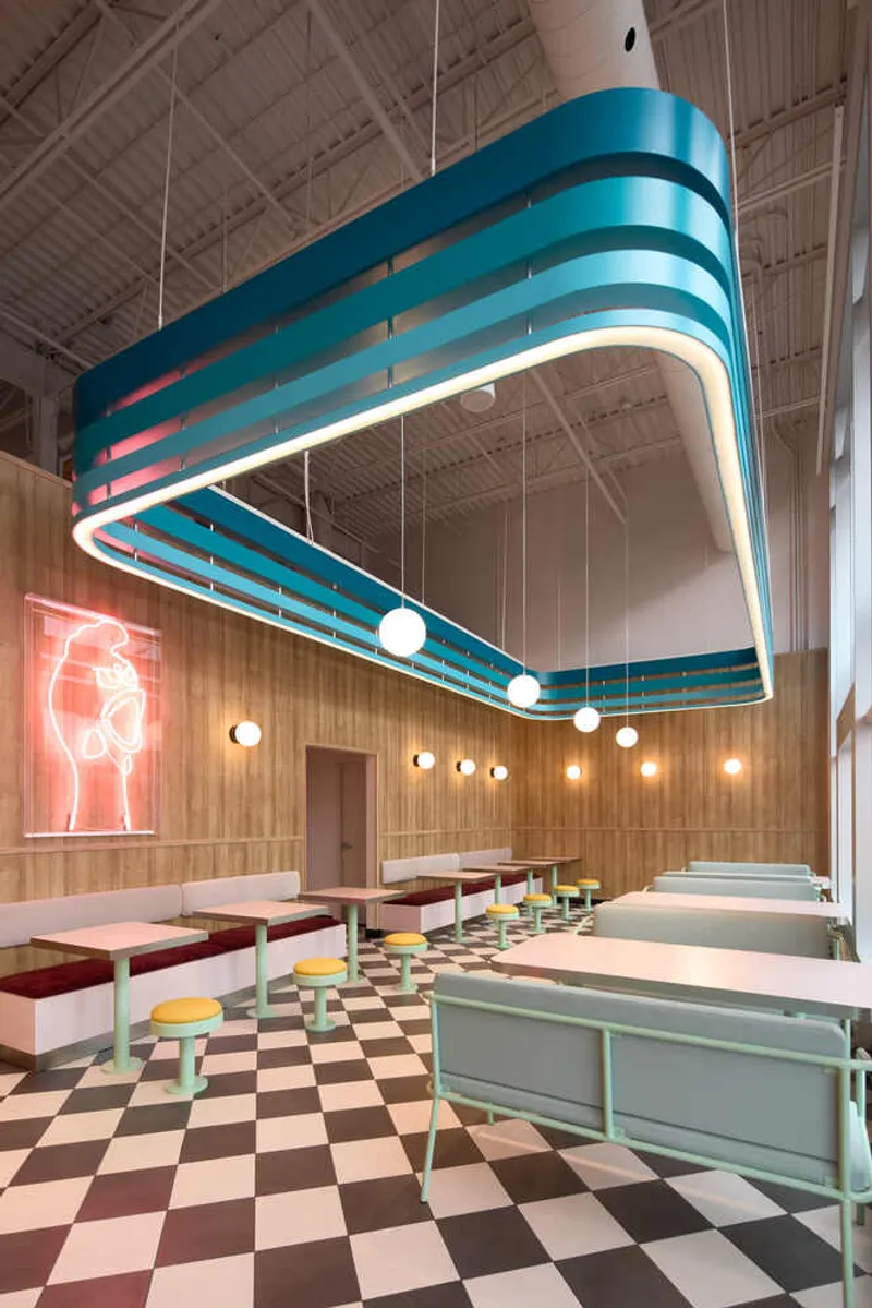 Dining area with suspended blue banded canopy above checkered floor and banquette seating