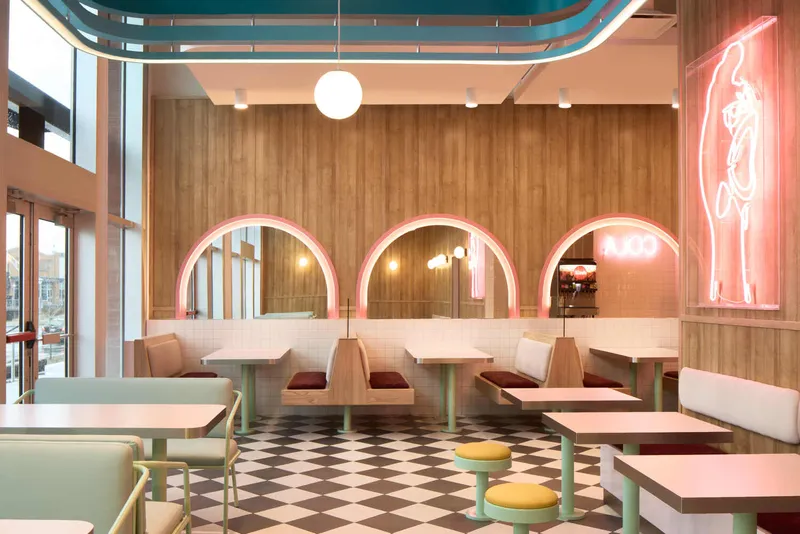 Three pink neon-lit arched openings set into white tiled half-wall with wood paneling above