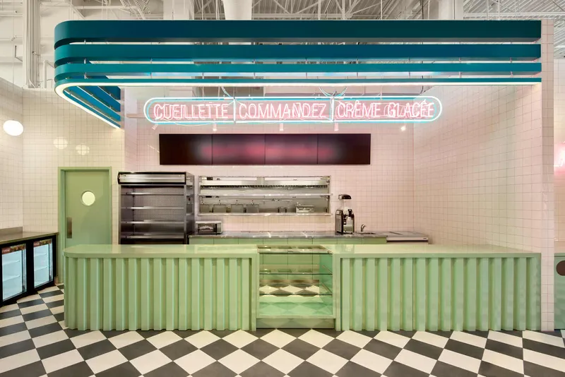 Service counter with ribbed mint green base below pink neon signage and white tile wall