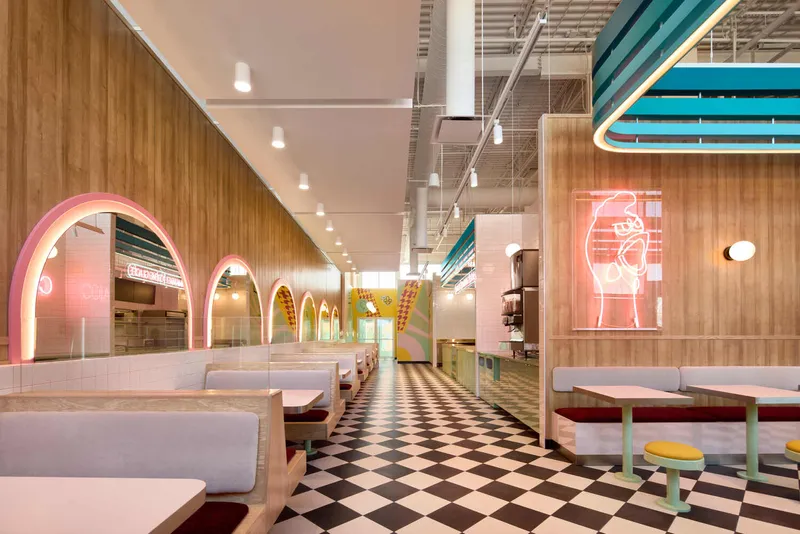 Long view through dining room showing checkered floor and pink arched partitions under exposed ceiling