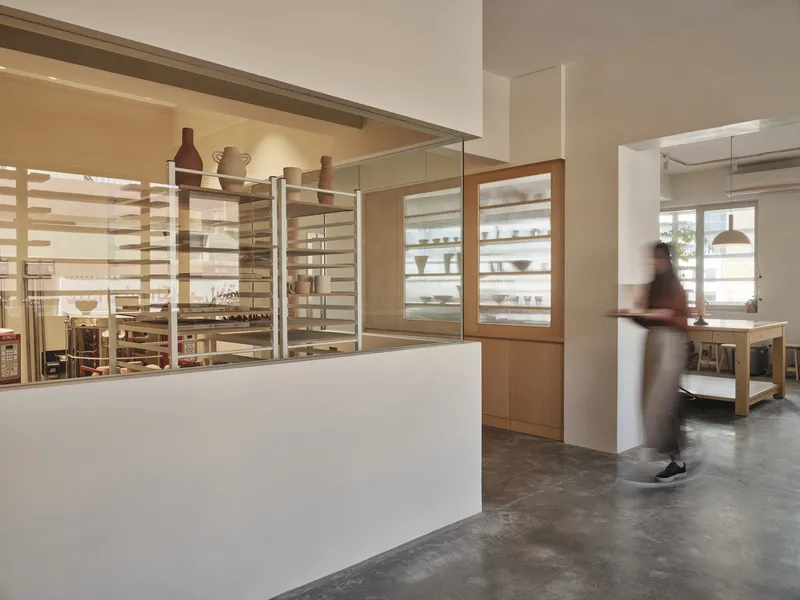 Glass-topped display counter with timber shelving beyond and a person walking on polished concrete flooring