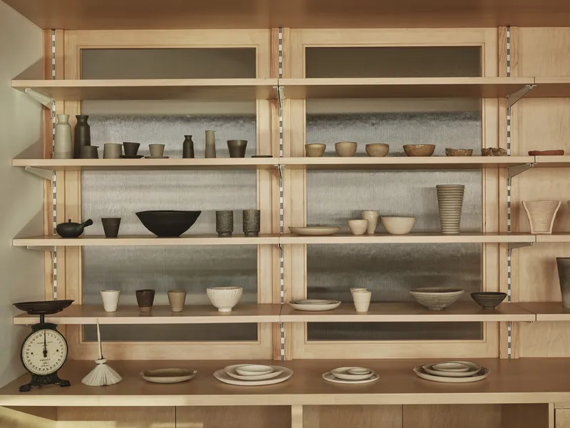 Plywood shelving system with adjustable tracks displaying ceramic bowls and vessels with felt backing