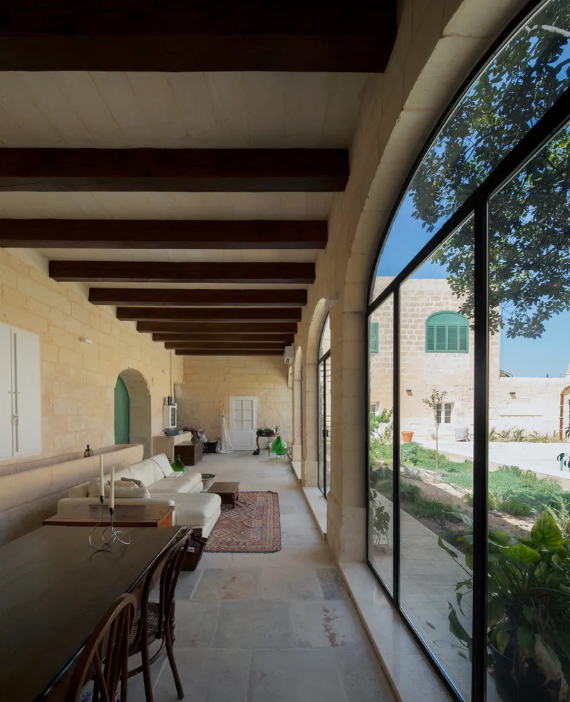 Covered gallery with exposed timber beams and full-height glazing overlooking the planted courtyard