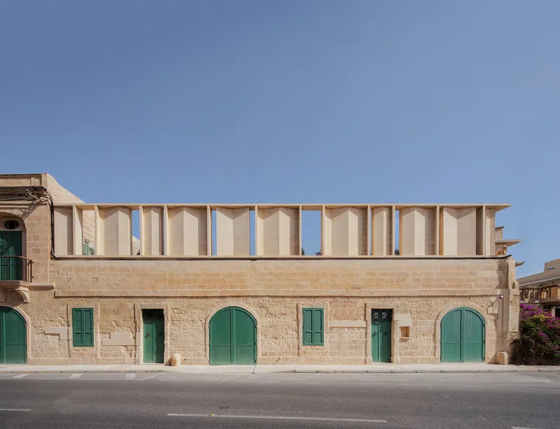 Street facade showing timber colonnade atop a limestone base with green arched doors