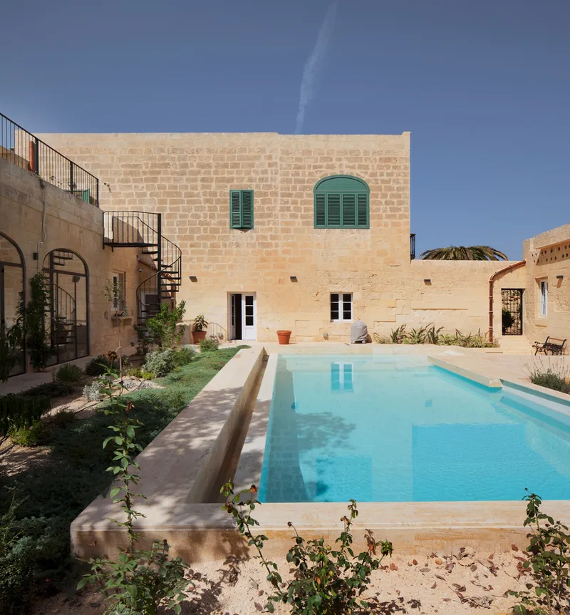 Courtyard showing the pool edge and limestone walls with green shuttered windows