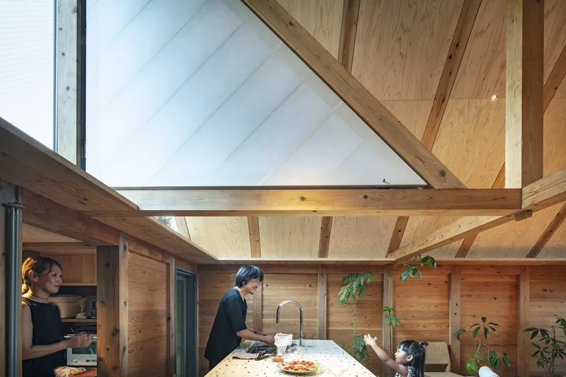 Kitchen island with two occupants preparing food under vaulted timber ceiling with clerestory glazing above