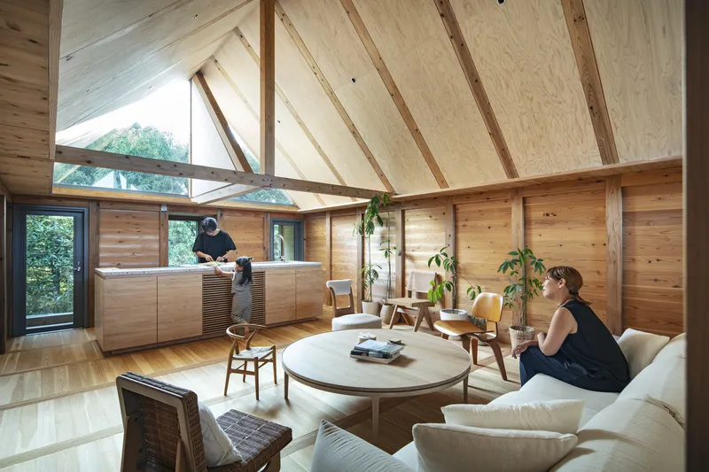 Open living room with exposed timber rafters and plywood ceiling beneath a clerestory window