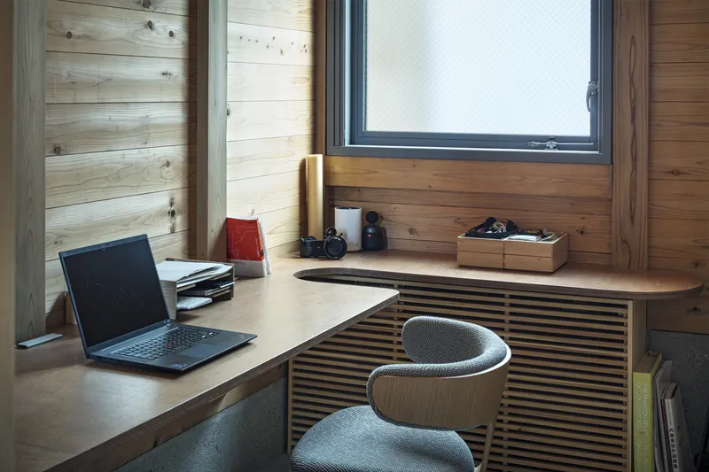 Built-in desk corner with slatted timber panel below a black-framed window